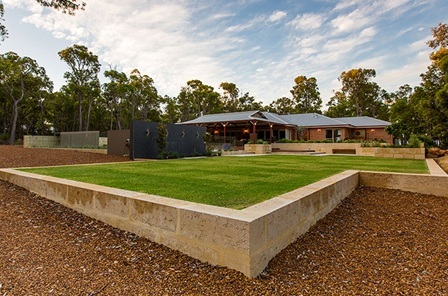 Landscaping featuring retaining walls and grassed area
